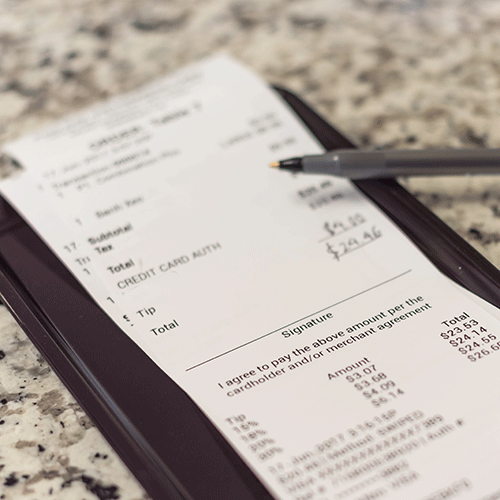 receipt on plastic tray with hand written total amount and suggested gratuities