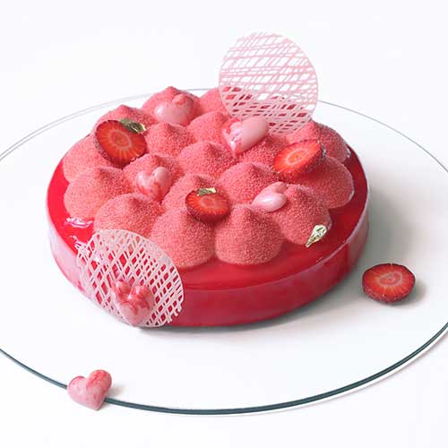 strawberry entremet covered with red velvet spray and red mirrored glaze