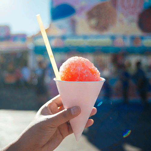 close up of red snow cone in white paper cone