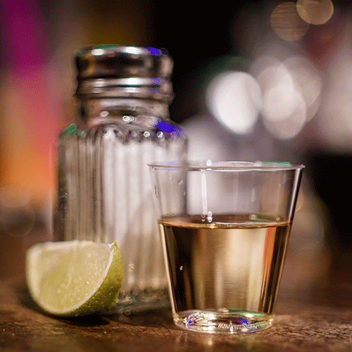 shot of tequila with salt shaker and lime in background
