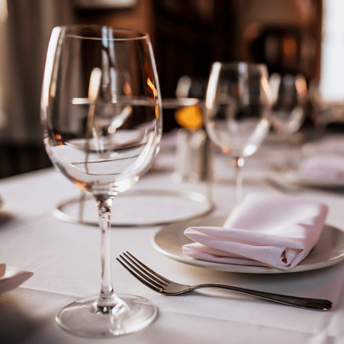 close up shot of a restaurant table set up with tableware and wine glass