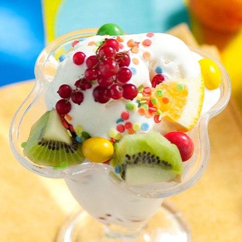 ice cream topped with kiwi, oranges, berries and sprinkles
