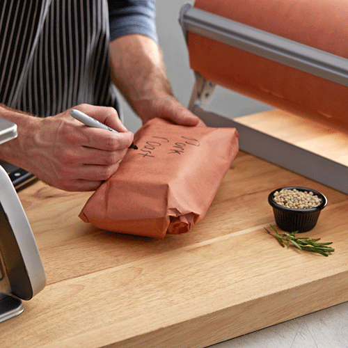 person writing on meat wrapped in butcher paper