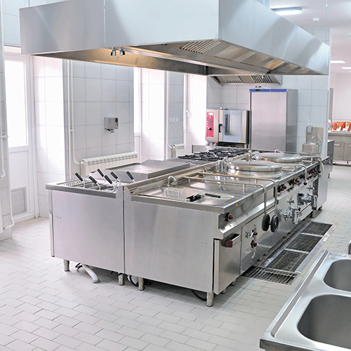 stainless steel deep fryers and commercial kitchen appliances under a kitchen hood