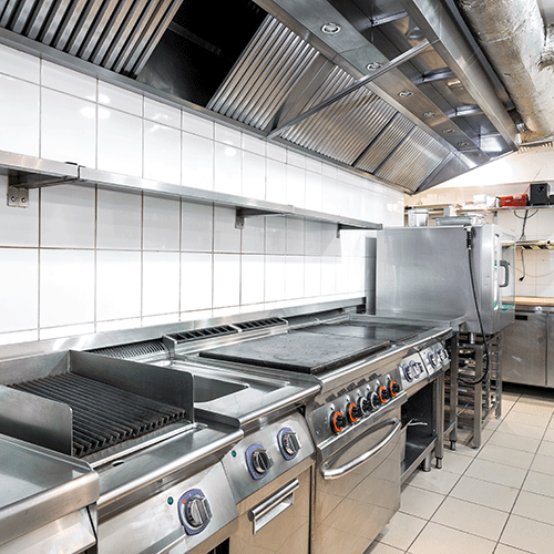 stainless steel griddles under extraction hood in a commercial kitchen
