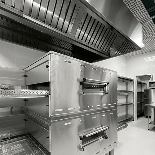 stainless steel pizza ovens and shelving units in a commercial kitchen