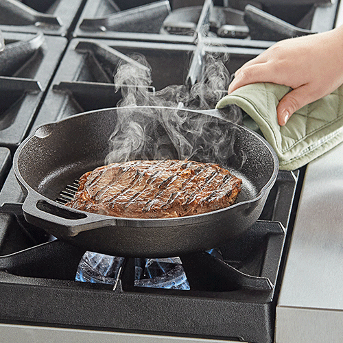 a seasoned cast iron grill pan with steaks