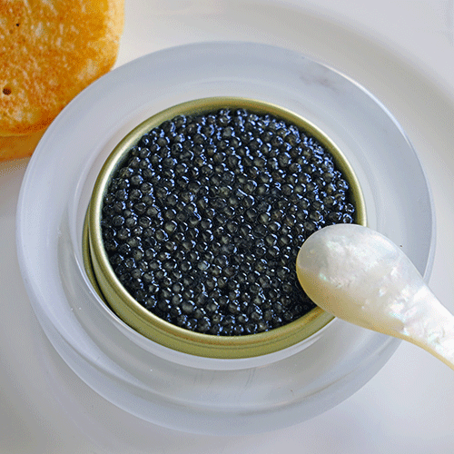tin of black sturgeon caviar with blinis and a mother of pearl spoon