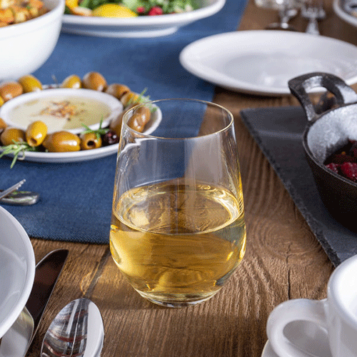 white wine in a stemless glass on a wooden table with olives