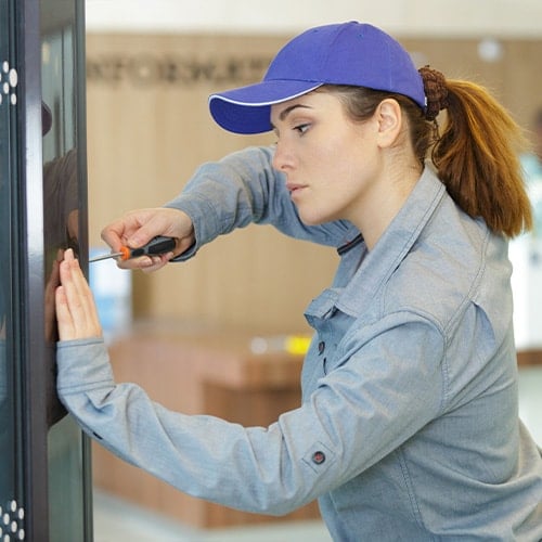 woman in a blue hat repairing a broken vending machine