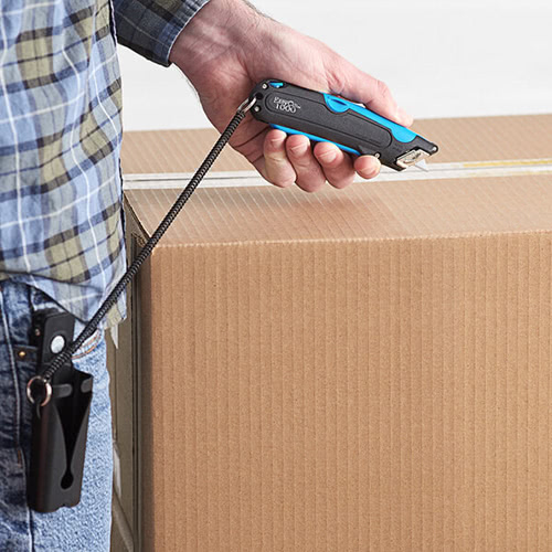 man holding a box cutter with clip on holster and tether by unopened box