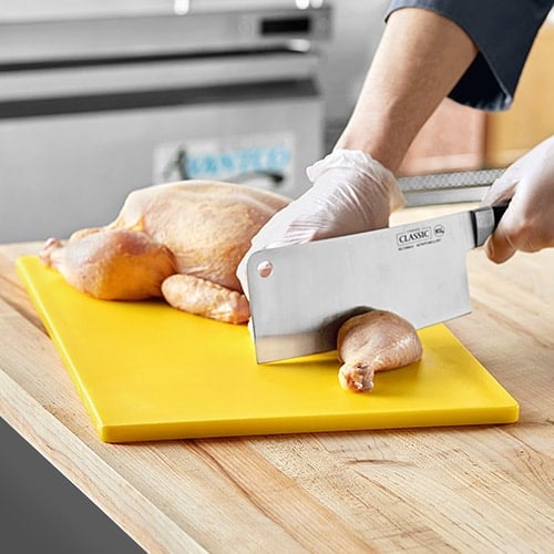 cutting chicken on a yellow cutting board