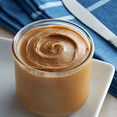 jar of creamy peanut butter with a blue napkin underneath