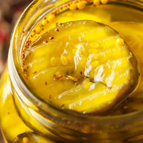 sliced bread and butter pickles in a glass jar