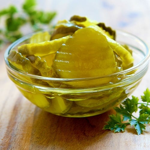 sliced sweet pickles in a glass bowl