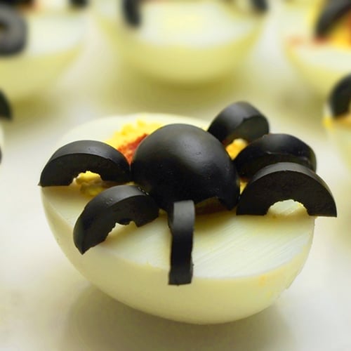 deviled eggs topped with spider shaped olives