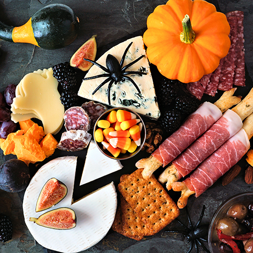 charcuterie board with cheeses, figs, pumpkin, meats, and candy corn
