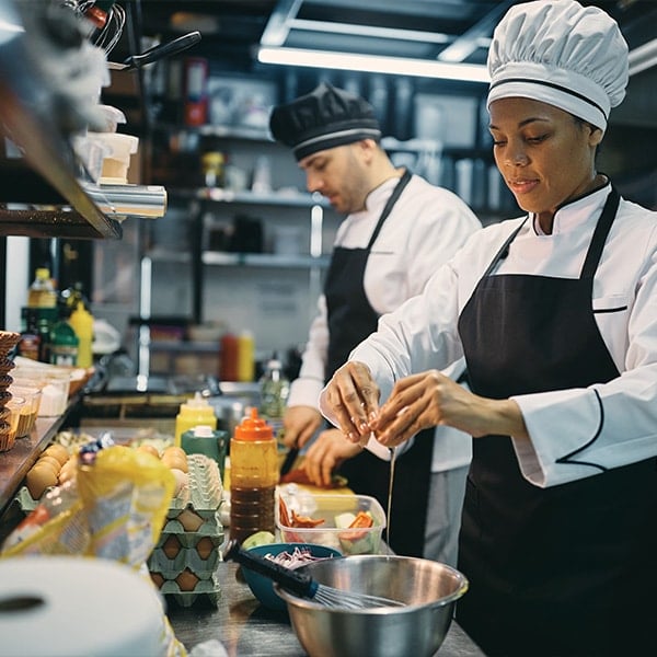 chef cracking an egg while preparing food in restaurant