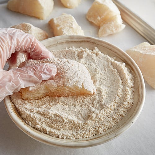 Chef dredging raw fish through flour