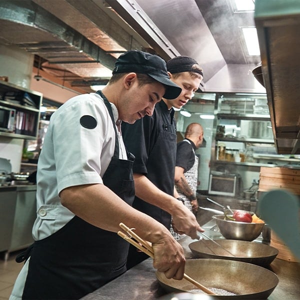 two chef assistants cooking a new dish in a restaurant kitchen
