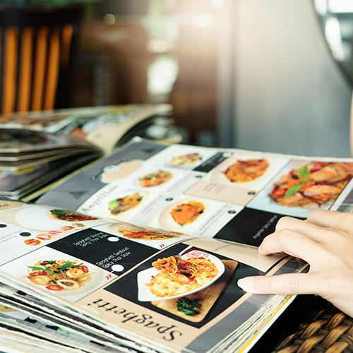 hand holding open colorful restaurant menu