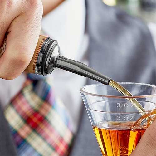 Liqueur being poured into a clear jigger