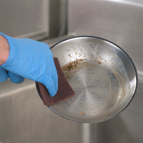 https://www.webstaurantstore.com/uploads/blog/2023/1/cleaning-stainless-steel-pans_scrubbing.jpg