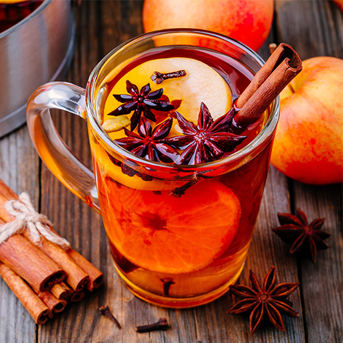 Hot mulled apple cider with with cinnamon sticks, cloves and anise