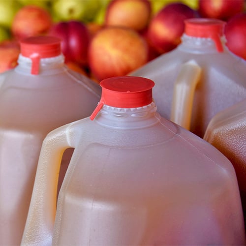 Apple cider in jugs with apples at the farmers market