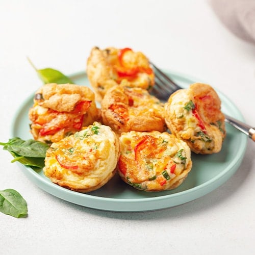 egg muffin bites and spinach leaves on a plate with a gray background
