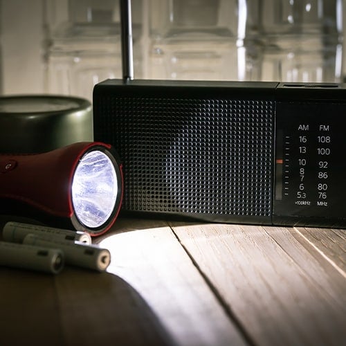 flashlight, radio, and batteries on a table in a dark room