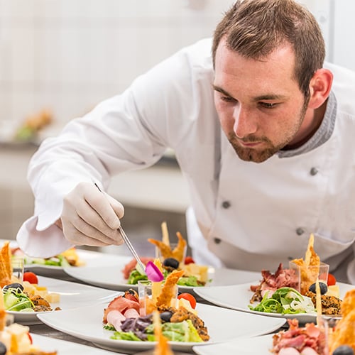 a chef examining the presentation of a row of plates