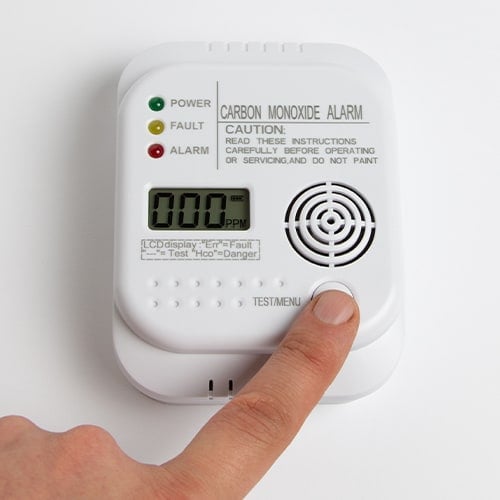 person pressing the test button on a carbon monoxide detector