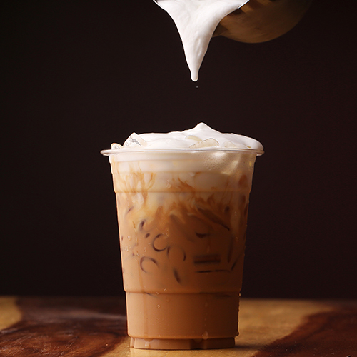 cold foam being added to a cup of iced coffee