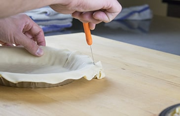 Add your prepared bottom crust to the pie pan and trim off the excess dough with a knife or kitchen shears.