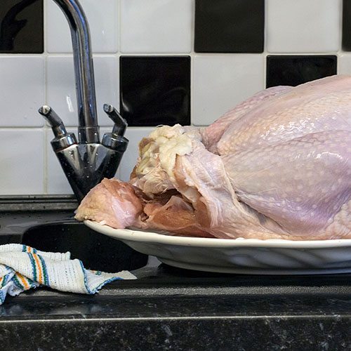 Raw poultry defrosting in a domestic kitchen next to a sink