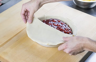 Lay the prepared top crust on top of the filled pie.