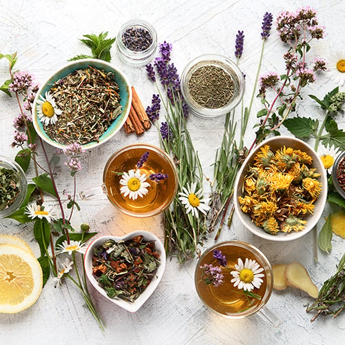 Floral loose leaf tea ingredients alongside brewed cups of floral tea