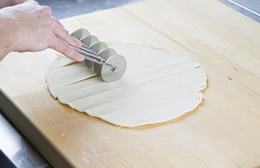 Use a pastry wheel or dough cutter to cut the prepared top crust into 1 inch strips.