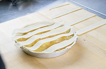 Lay half of the strips vertically and evenly spaced on top of the filled pie.  Leave about 1/2 inch of space between each strip to allow for weaving.