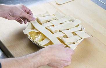 Take the next set of vertical strips and fold them back, placing another horizontal strip over them. Unfold the folded strips and repeat the process until you have completed the lattice pattern across the entire pie.
