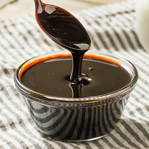 bowl of molasses with a spoon dipping into it