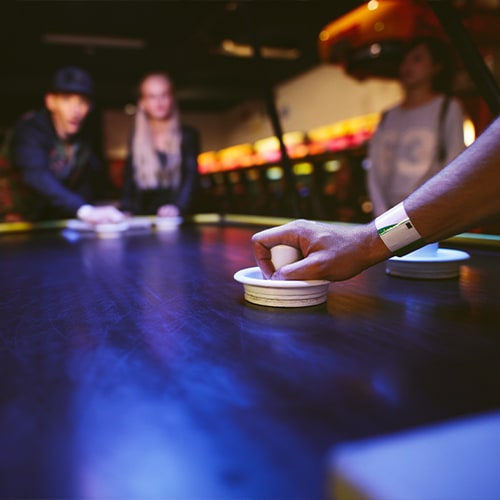 people playing air hockey in a bar