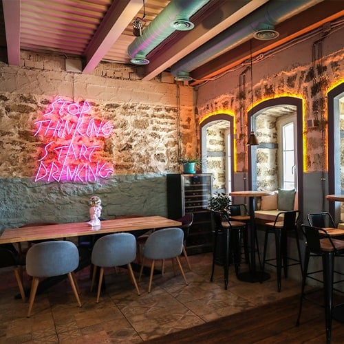 restaurant interior with modern decorations and neon word sign on a stone wall