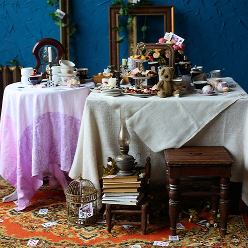 tables decorated with books, card, and teacups for an alice in wonderland theme tea party