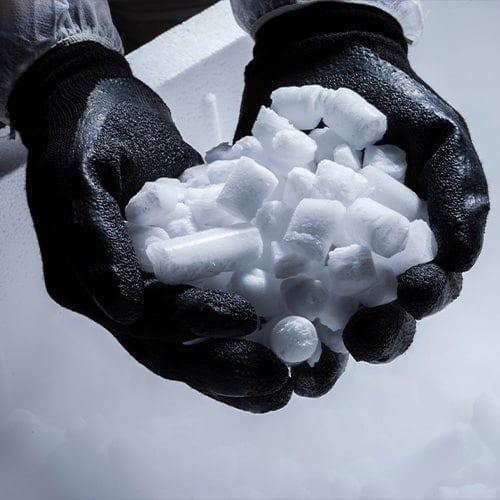 Worker holding dry ice pellets with thick black gloves