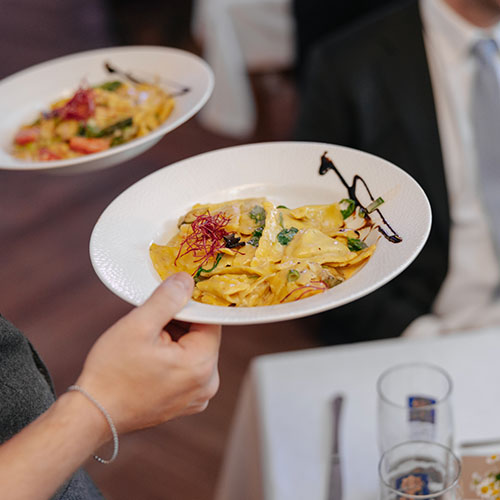 pasta being brought to the table by the waiter