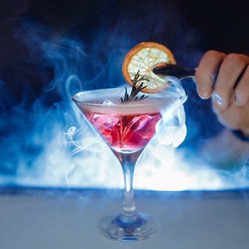 fancy cocktail with smoke and a lemon garnish