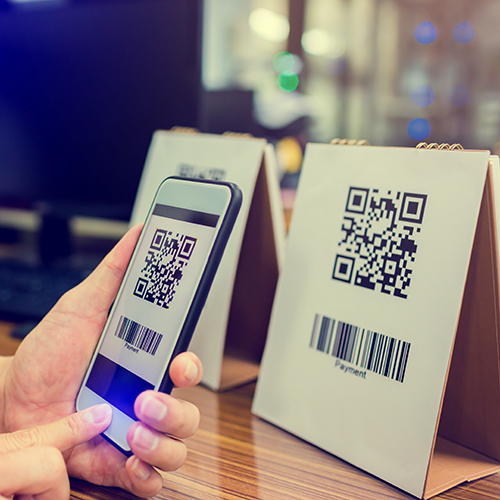 person scanning a QR code posted on a table