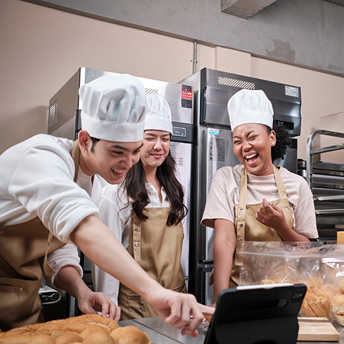three young chefs in aprons laughing